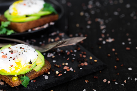 Rye toasts with sliced avocado and poached eggsの写真素材