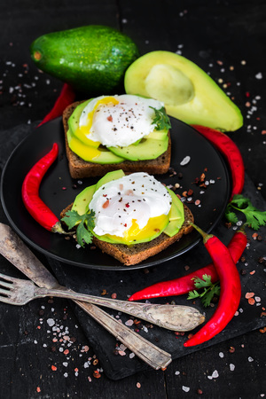 Rye toasts with sliced avocado and poached eggsの写真素材