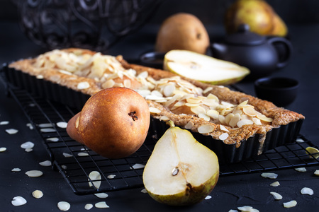 Frangipane tart with poached pears and almond petals. Low key.の写真素材