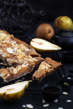 Frangipane tart with poached pears and almond petals. Low key.の写真素材