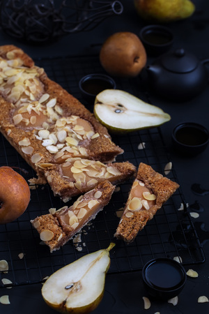 Frangipane tart with poached pears and almond petals. Low key.の写真素材