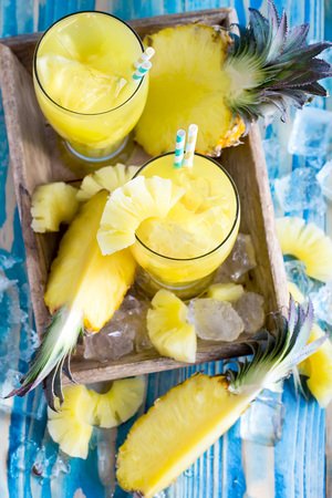 Pineapple juice and fresh ripe pineapple on wooden backgroundの写真素材
