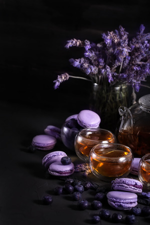 Tea in the glass teapot with lavender and blueberry macarons. Copyspace background.の写真素材