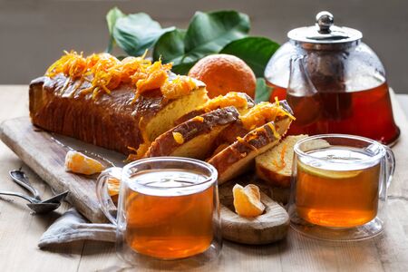 Glazed orange cake with tangerine jam topping and tea with lemonの写真素材