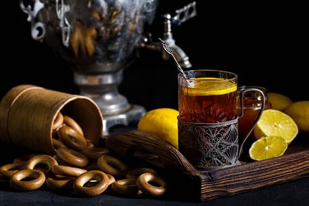 Russian tea in glass with glass holder, samovar, lemon, honey and sushkiの写真素材