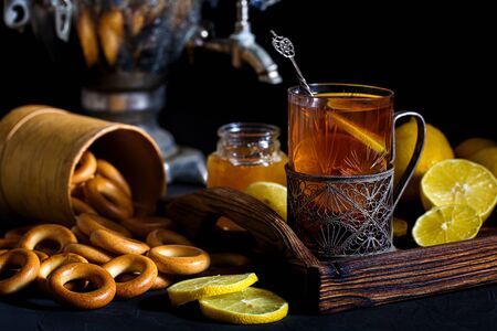 Russian tea in glass with glass holder, samovar, lemon, honey and sushkiの写真素材