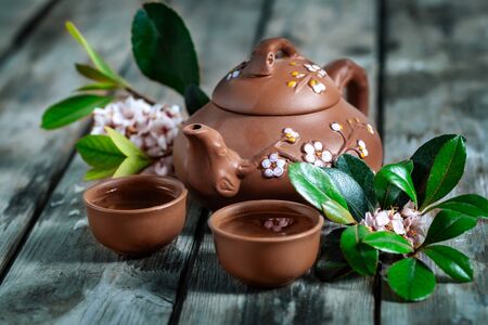 Tea in small brown yixing teapot and spring blossom on old wooden backgroundの写真素材