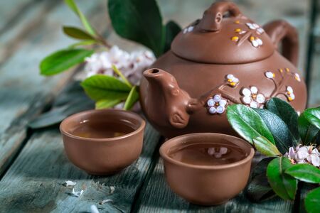 Tea in small brown yixing teapot and spring blossom on old wooden backgroundの写真素材