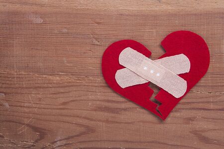 Red broken heart sign on wooden background. Broken heart, love and valentines day concept.