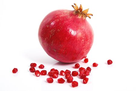 Some red juicy pomegranate, whole and broken, on white table.の写真素材