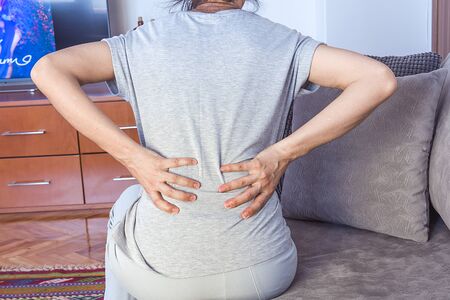 The woman is touching her aching waist. Low back pain concept. Health concept.