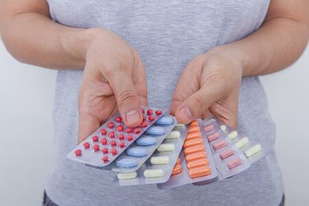 The woman is holding some medicine tablets in her hand.の写真素材