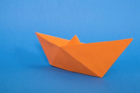 Orange paper ship on blue background.の写真素材
