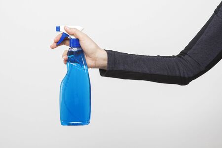 The woman is holding a blue water foggy spray detergent bottle in her hand. Blue spray bottle.