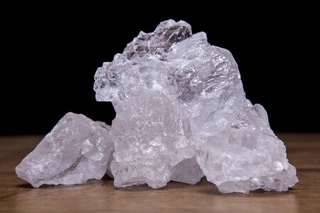 Coarse granules of natural rock or sea salt on a rustic old wooden table.