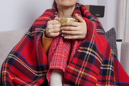 The woman is holding a cup of hot sage. The woman is sick and the weather is cold.
