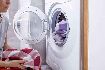The woman is washing the laundry. The concept of cleaning. Housewife woman in laundry room with...