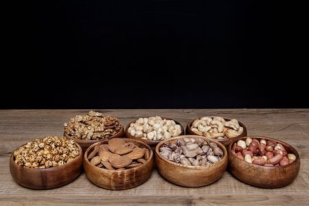 Different mixed nuts in a bowls on wooden table. Healthy food and snack.の写真素材