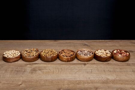 Different mixed nuts in a bowls on wooden table. Healthy food and snack.の写真素材