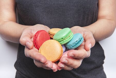 Sweet and colorful macaroons or macaron woman's in hand on white background.の写真素材