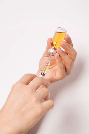 The doctor is holding medicine bottle and syringe.