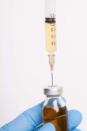 The doctor is holding medicine bottle and syringe.