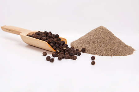 Black pepper in wooden spoon, ground black pepper isolated on white background.