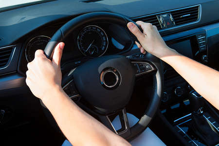 Close up of female hands on the steering. Traveler girl on car trip.の写真素材