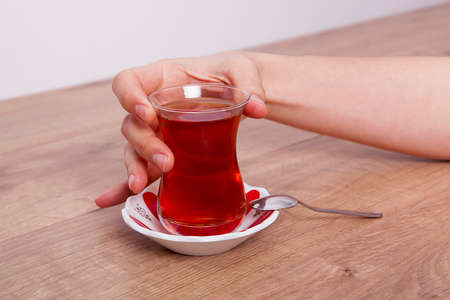 One cup of tea woman's in hand on wooden background.の写真素材