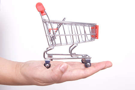 Small toy shopping cart in the hands of the woman doing internet shopping. Internet shopping concept.の写真素材