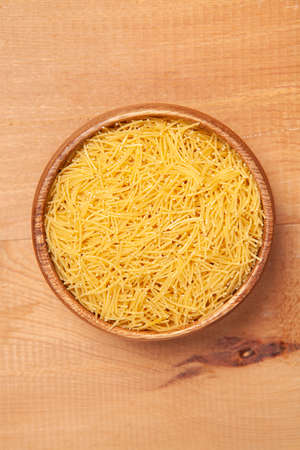 Vermicelli in the wooden plate on wooden background.の写真素材