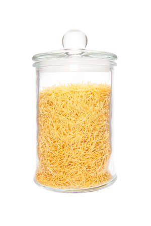 Uncooked vermicelli in glass jar on white background.の写真素材