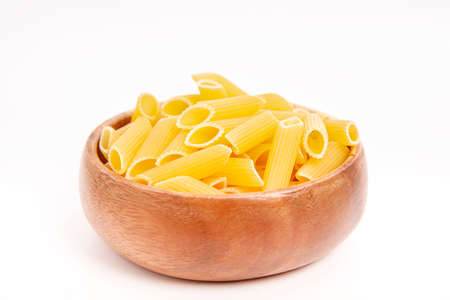 Uncooked cake in wooden bowl on white background. Pasta in the shape of a pencil.の写真素材