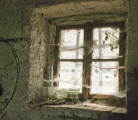 Old window in a stone wall with glasses covered with spider's web