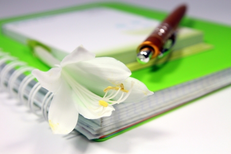 Notebook with a pen and white flowerの写真素材