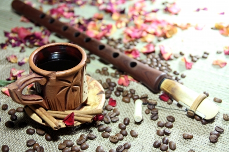 Still life with ceramic cup of coffee, Armenian musical instrument duduc and coffee grains on background with petals of rosesの写真素材