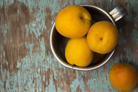 Apricots in  aluminum mug on rustic wooden surface. Top wiew.の写真素材