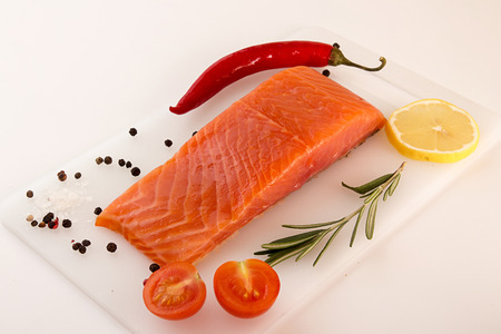 Salmon fillet, chili pepper, lemon slice and tomato over on white background. Healthy food concept.