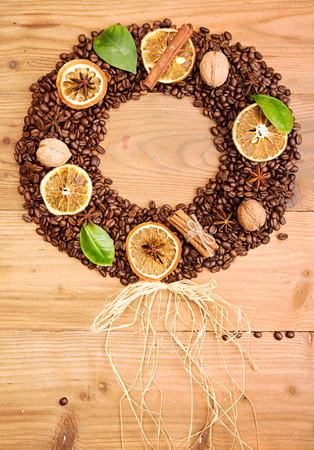 Coffee background. Heap roasted coffee beans in shape of circle wreath with dry orange, coffee leaves and cinnamon. Top view. View from aboveの写真素材