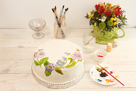 Painting cake with food colorings. Round cake with fondant and painted flowers. Cake with pansiesの写真素材