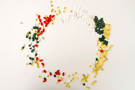 Pills background. Circle of assorted various medicine tablets and pills different colors on white background. Healthcare or medicament addiction concept. Copy space.の写真素材