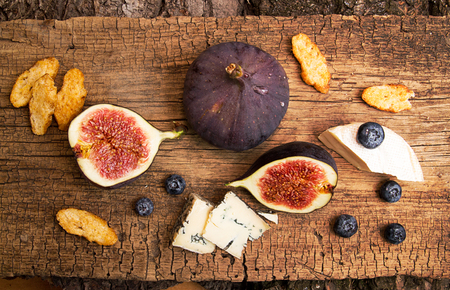 Figs, half of figs, brie and blue cheese on old wooden background. Dieting healthy eating concept. Top view. Rustic styleの写真素材