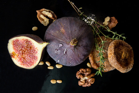 Figs, dried figs, half of fig, walnut and pine nuts on black background. Dieting healthy eating concept. Top viewの写真素材
