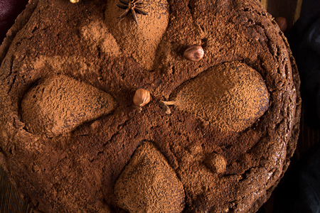 Chocolate cake with pears stewed in red wine, hazelnuts, walnuts. Traditional dessert. Top view.の写真素材