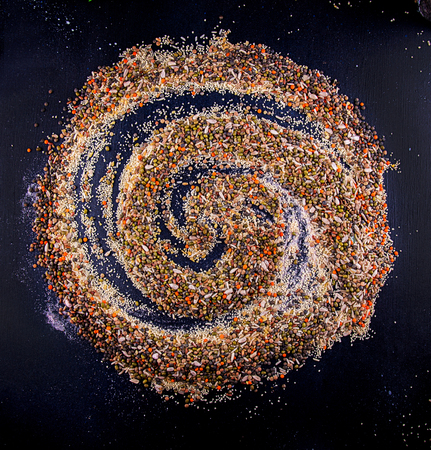 Food background. Swirl of various Legumes, sereals, beans, grain and seeds on dark background. Kind of lentils, bulgur, mash, chickpeas, sunflower seeds, couscous, rice.の写真素材