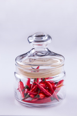 Red small spisy chili peppers in glass jar.の写真素材