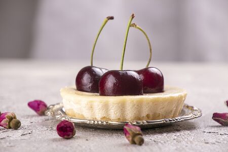 Small portion cheesecake with fresh sweet cherries against of gray backgroundの写真素材