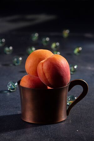 Natural organic apricots in vintage cooper cup over on dark backgroundの写真素材