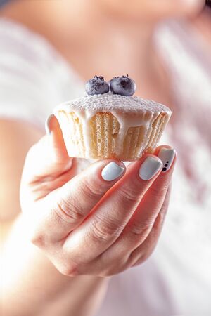 Iced sugar muffin with blueberry in woman handの写真素材