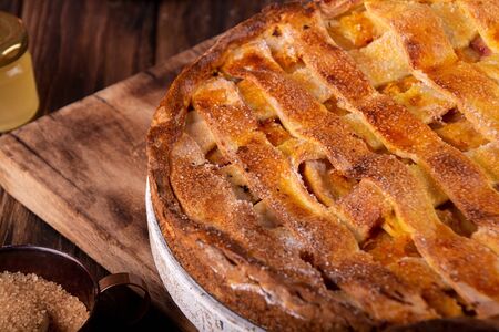 Homemade sweet pie cake with peach on white board on wooden rustic background.